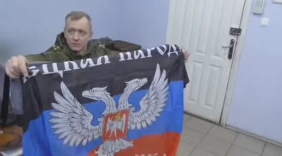 Российский офицер держит флаг ДННР, иллюстрация Российский офицер держит флаг ДННР, иллюстрация