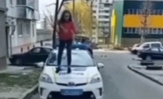 Девушка взобралась на капот авто полиции / Скриншот
