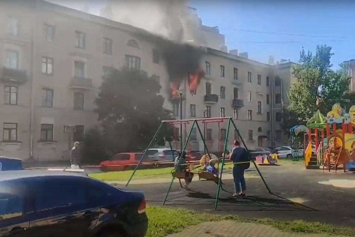 Катающиеся на качелях дети на фоне полыхающего дома в Питере 